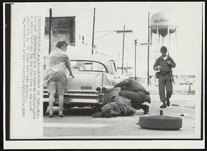 Guardsmen Fix Flat--Miss. National Guardsmen, on duty in downtown Gulfport, give a helping hand and fix the flat tire as the winds still whip in the coast city this morning.