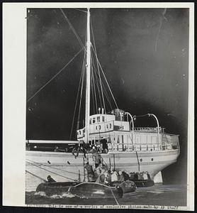 Immigrants, Jewish reach blockade runner. Palestine-bound immigrants board the “Al Tafchidunu” from bobbing rubber rafts. Two-masted schooner.