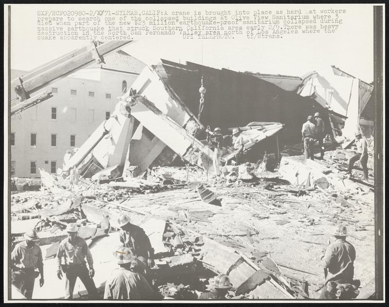 A crane is brought into place as hard hat workers prepare to search one of the collapsed buildings at Olive View Sanitarium where 3 died when part of the new $23 million "earthquake-proof" sanitarium collapsed during massive earthquake that struck Southern California area early 2/9. There was heavy destruction in the North San Fernando Valley area north of Los Angeles where the quake apparently centered.