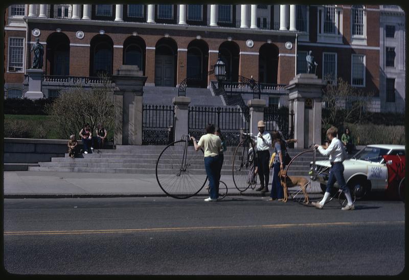 Three people with pennyfarthings in front of the Massachusetts State