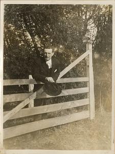 Unidentified man leaning on gate