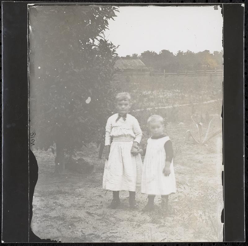 Two boys in a field with barn in distance