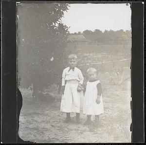 Two boys in a field with barn in distance