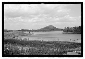 A body of water, a hill in the distance