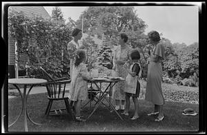 Group of women and children eating and talking in the garden