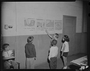 Children reading story on wall of classroom