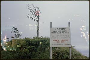 Double exposure of sign with information on razor clam digging and cityscape at night