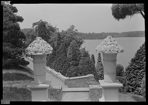 Italian gardens and lake, view through stone carved urns at Walter Hunnewell's