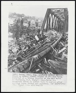 Flood Wrecks Bridge- Piled up debris covers tracks of the New Haven railroad at a broken trestle on the New Haven to Maybrook, N.Y. freight line. Below the Naugatuck River is almost back to normal after raising havoc friday and saturday.