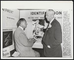 Displays Baby Identification Clamp--Dr. J. Bay Jacobs, left, of Arlington Hospital, Arlington, Va., displays what is termed a virtually foolproof identification clamp to prevent possible baby mixups in hospital. The clamp was demonstrated to doctors today at the seventh American Congress on Maternal Care. Looking on is Dr. Frederick H. Falls, River Forest, Ill., president of the group.