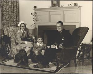 An unidentified man in military uniform, an unidentified woman in a nurse's uniform, a boy and dog