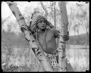 A man wearing Native American headdress and clothing posing outdoors