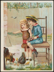 Boy sitting on a chair while a girl stands feeding chickens.