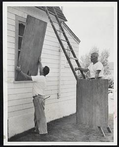 John and Chester Emol put up wooden blinds to protect windows on their cottage on Beach St., Nantasket. Hurricane warnings have been issued for southern New England coastal areas.