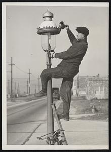 Lamplighting at Dusk Still Continues .. A familiar sight to remote south side Chicagoans is the lamplighter who rides his wheel slowly from block to block stopping at every corner and lighting his old time gas-fed street lights. Ancient and out-moded perhaps but the few remaining are lights are faithfully tended by a lamplighter who carries a blowtorch, a can of oil and has a definite lighting technique for each lamp so it will cast forth the proper mellow glow.. Photo shows John Basso whose daily occupation is the lighting the old time gas-fed street lights..