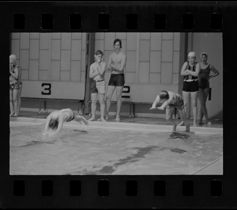 Two swimmers jumping into YWCA pool, with onlookers