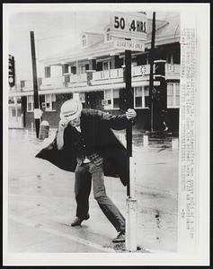 An unidentified man grabs hold of a sign post to keep from being blown down the street here 8/28 as hurricane "Cleo" approaches.