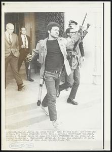 Armed March--With raised fists and carrying rifles, two Negro students march from a Cornell University building, ending a 36-hour seige by sine 100 Negro students on the Ithaca, N.Y., campus yesterday. University officials follow the students at left.