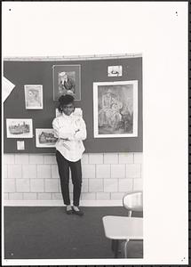 Young woman standing in front of art work in a classroom