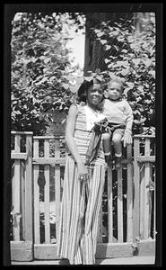 Constance Miller stands holding a toddler