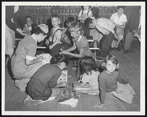 Dedham Flood Victims-Red Cross worker Marie Maida, left, plays with youngsters whose families were forced to evacuate their homes in the East Dedham section late yesterday because of flood waters. The Red Cross set up a relief station at the I and A Club in East Dedham spuare.