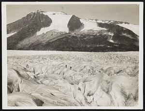 Rock And Ice. Two members of the father Hubbard party crossing the miles wide stretchers of the Mendenhall Glaciers as they made their way towards the higher levels of the ice cap. Glacier Priest reveals mountainous vistas. Two members of the Fr. Hubbard’s party crossing a stretch of the Mendenhall glacier in Alaska. Fr. Hubbard is shown in the circle.