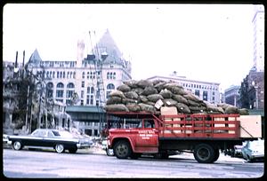 Truck loaded with bags next to demolished building