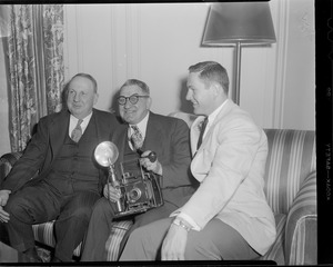 Men sitting on couch with speed graphic camera