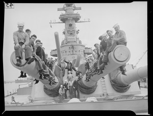Men sitting on battleship's big gun