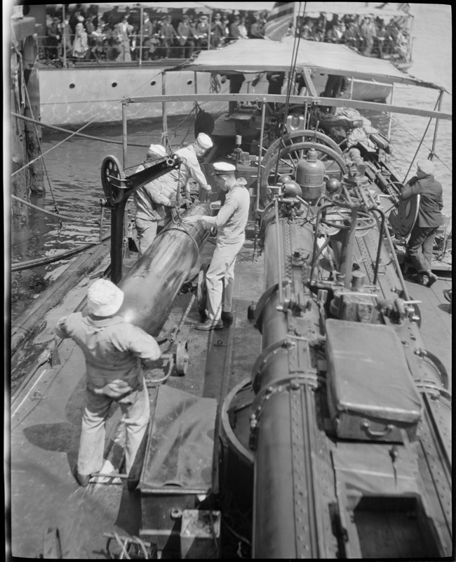 Seamen working on torpedo on deck of ship