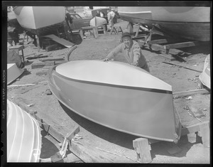Man works on hull of boat in yard (For Chet Ross)
