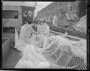 Asian youths examine nets aboard trawler at fish pier