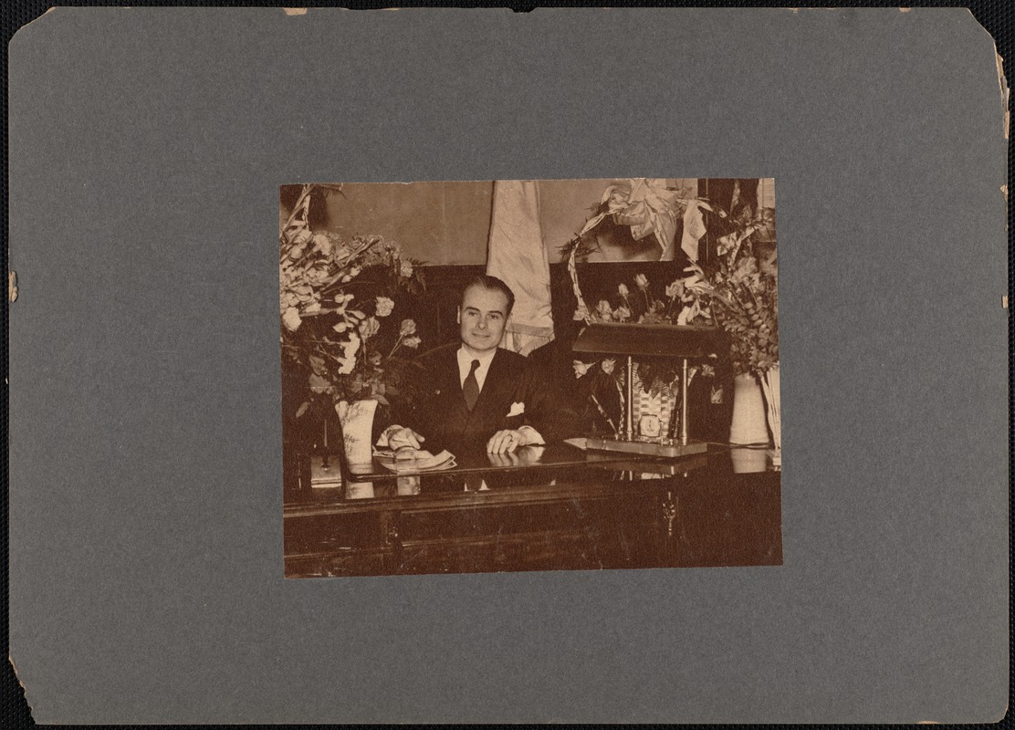 New Bedford mayor Matthew A. Glynn at desk with vases of flowers