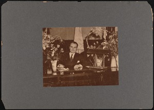 New Bedford mayor Matthew A. Glynn at desk with vases of flowers