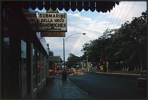 View of rainbow past sandwich shop, pharmacy, and construction area, Powderhouse Square, Somerville, Massachusetts