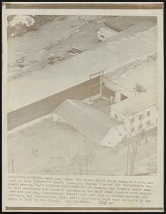 East Lee, Mass. The flash flood which damaged homes, and land in this Berkshire County community Sunday flooded the Clark-Aiken Co. plant causing eight million dollars worth of damage. The company makes paper mill machinery and related equipment. One mile away, houses were uprooted and one man, 60-year-old Edward Gage was killed. Rescue workers are searching for 55-year-old Mrs. Olive Courtinier who's home on Route 20 was split in half by the flood.
