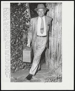 Hurrying off to Work--Presidential Assistant Sherman Adams appears in a hurry as he swings through the rustic gate to his home today upon leaving for his White House desk. President Eisenhower is expected to comment at his news conference later in the day on the furor that has arisen over influence charges directed at his top aide.