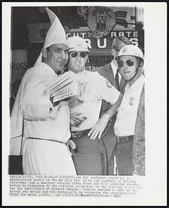 Klan Leaflets--As two policemen stand by, an unidentified member of the Ku Klux Klan hands out leaflets in Atlanta yesterday near a downtown Atlanta hotel which had been picketed shortly before by delegates to the national convention of the National Association for the Advancement of Colored People. Pickets marched in fron of ten hotels and motels and six restaurants to emphasize the organization's fight for equal rights.