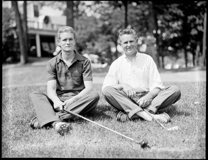 Two golfers seated on grass