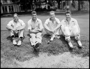 Four golfers seated on lawn in front of club house