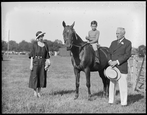 Grafton Smith with woman and boy on horse holding trophy
