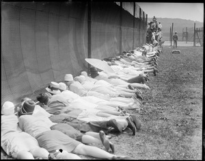 Onlookers lie on ground to look under fence, all to see Helen Wills play