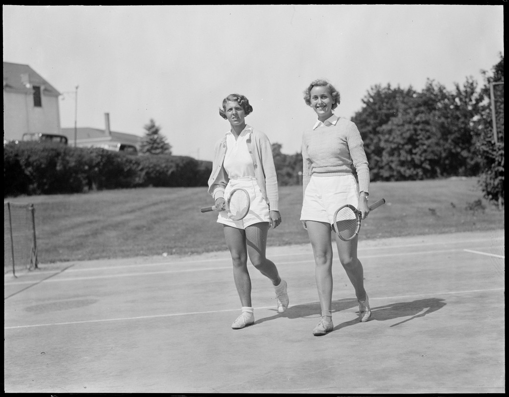 2 women carrying tennis rackets