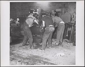 Three employees working on a machine