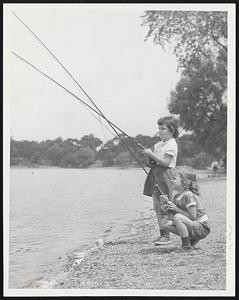 Tiny Anglers- Evelyn Murphy, 6, and her sister Terry, 4 1/2, try out some man-sized fishing poles as they practice for the Boston Park Department-Boston Traveler Fishing Rodeo to be held at Jamaica Pond on Tuesday, They live at 88 Jamaica St., Jamaica Plain.
