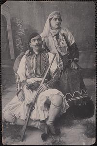 A Greek soldier poses with woman wearing traditional Greek dress