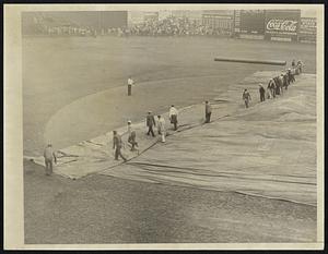 Uncover Field After Rain. Workmen removing tarpaulin from the field in Washington after one of the rainy spells before the third game of the World Series. It looked for a time as if the game would have to be postponed, but after the President came to throw out the first ball the sun shone.