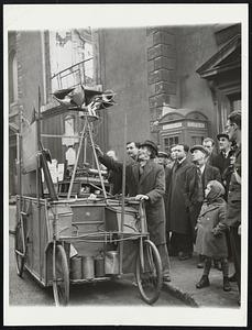 New "Bomber Destroyer". John Dyson, 63-year =-old "inventor", gets his "perfected bomber destroyer", which is mounted on a bicycle cart, ready for a tour of London street to impress the public, since British Government authorities remain indifferent to its potentialities. Mr. Dyson blames the "old-school-tie" crowd in the Government for the disinterest shown in his "working model". Mr. Dyson presses buttons, turns innumerable gadgets, and the steam whistles and something starts turning with squeaks of protest, and gradually the whole business starts whirling and bobbing up and down, and then, according to him, you are witnessing a model of the machine that will save any country from bombers. After lecturing the curious, he asks for coins so that he may continue his research and buy a new alarm clock, as new clock would help the cause.