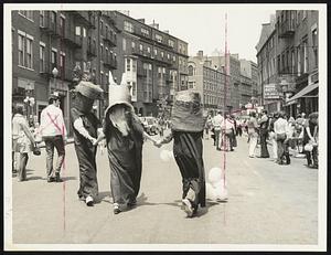 Masked Dancers perform in the street during "Peace Fair" held yesterday on Charles Street.