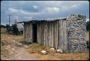 Small structure of wood and stone next to covered wagon